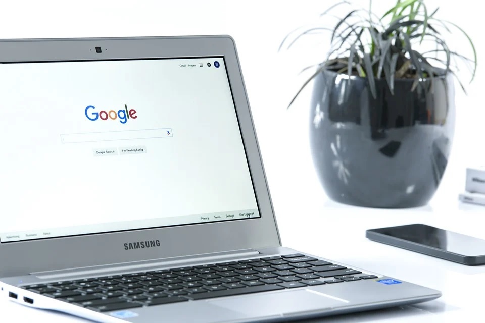 A silver laptop on a desk, displaying Google’s search engine page.