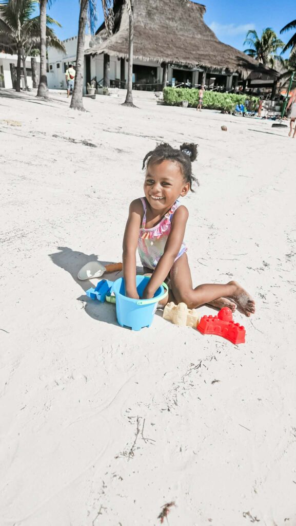 Young child worldschooling in Playa del Carmen building sandcastles on beach